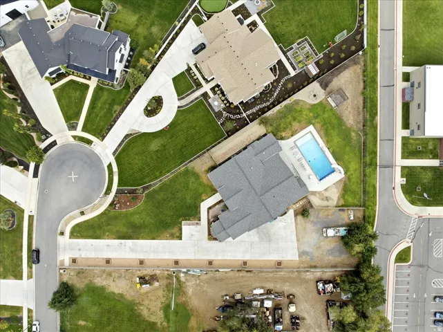 Property featuring a cul-de-sac, expansive green lawns, mature landscaping, a swimming pool with surrounding hardscaping, and paved driveways
