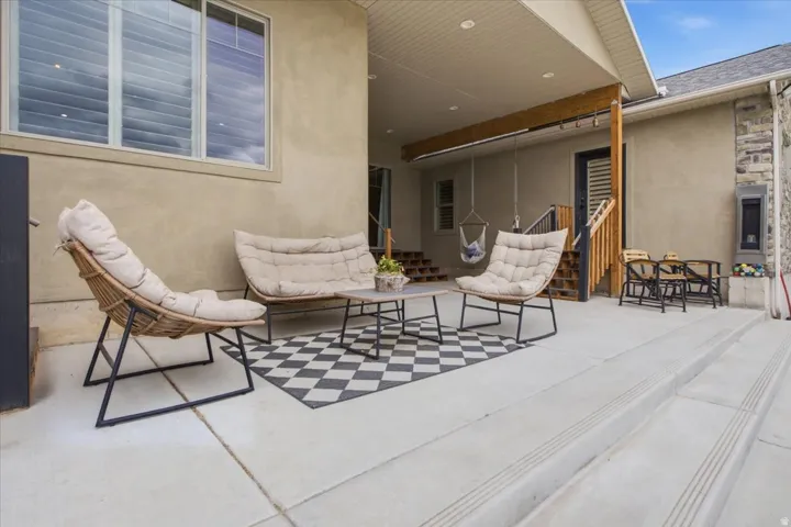 Covered patio with durable concrete flooring, a decorative stone accent wall, and wood structural beams