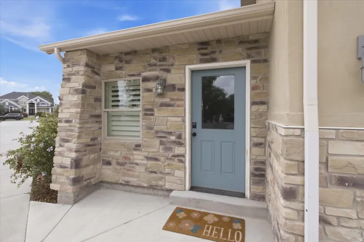 Stone veneer facade with a covered entry, light blue entry door with a clear glass panel, and a concrete walkway