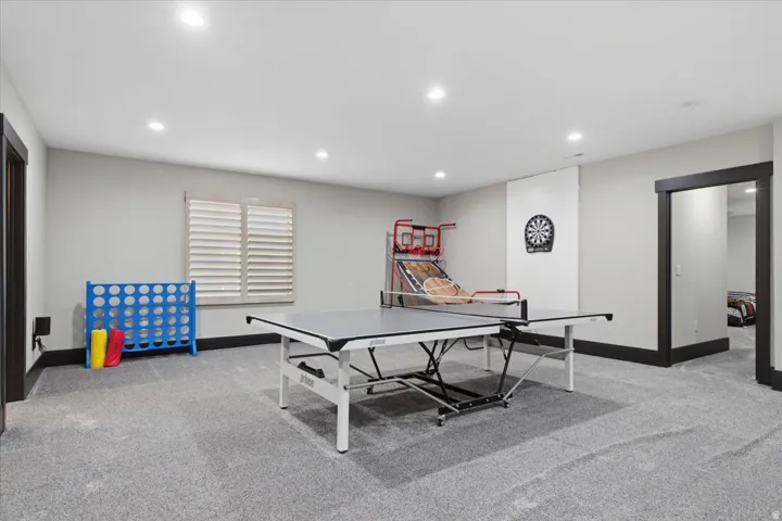 Expansive recreation room featuring recessed lighting, a window with plantation shutters, and dark trim details