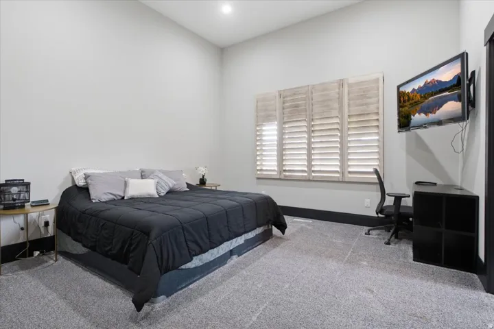 Recessed lighting, wood-finish window shutters, carpet flooring, and a wall-mounted television