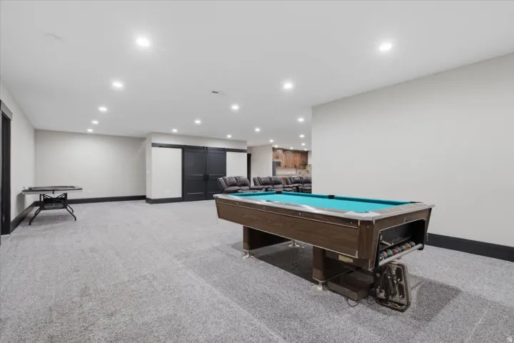 Expansive carpeted area featuring recessed lighting, dark trim, and dual dark barn doors