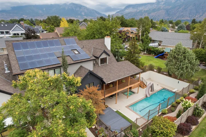 Rooftop solar panels, covered balcony, integrated hot tub, in-ground swimming pool with slide, and fenced yard