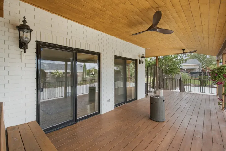 Expansive covered deck featuring wood-finish flooring, a natural wood paneled ceiling, and two ceiling fans
