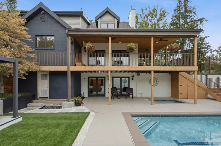 Two-story deck with wood railings, lower patio, integrated swimming pool, and spa