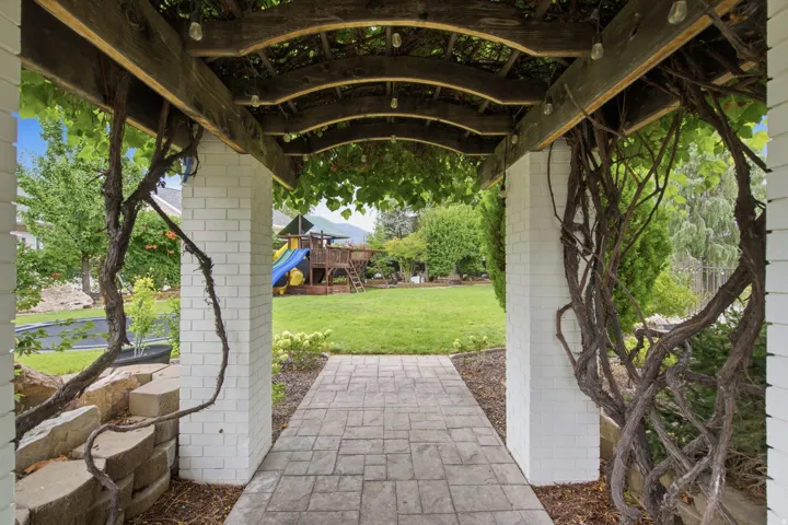 Wood-beam pergola with draped foliage and string lighting