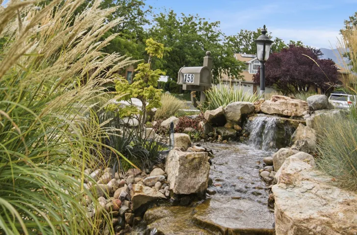 Landscaped water feature with natural rock elements, lush ornamental grasses, and a decorative lamppost