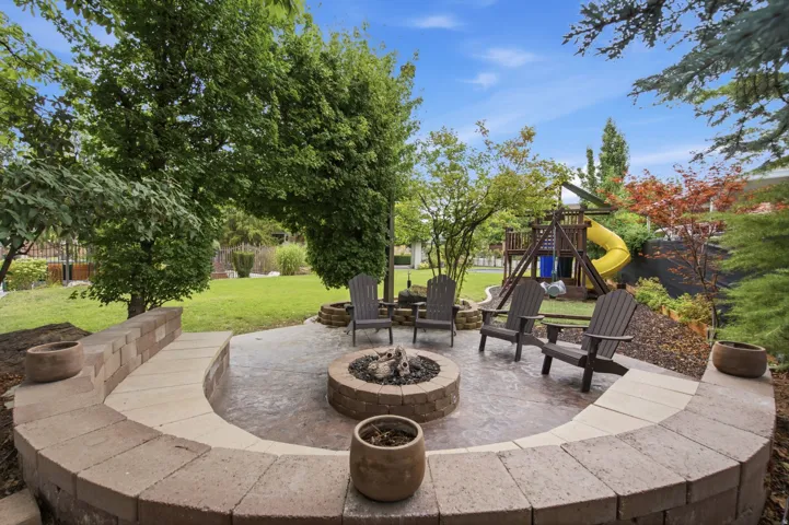 Patio with a built-in stone fire pit, stamped concrete surface, and a curved stone seating wall