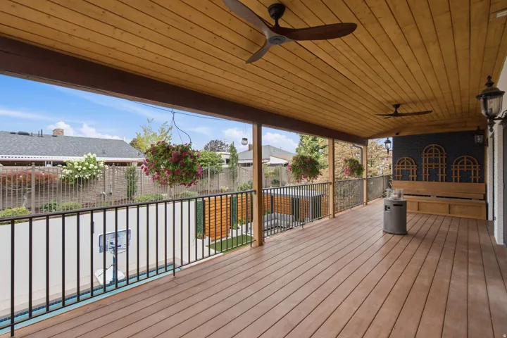 Expansive covered deck featuring wood-finish flooring, a natural wood paneled ceiling, and two ceiling fans