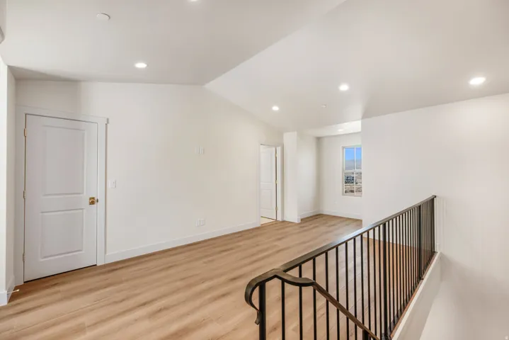 Expansive loft space with recessed lighting, wood-finish flooring, and a black wrought iron railing