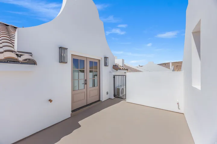 Private exterior patio featuring stucco walls, terracotta roof tiles, and French-style doors with glass panes