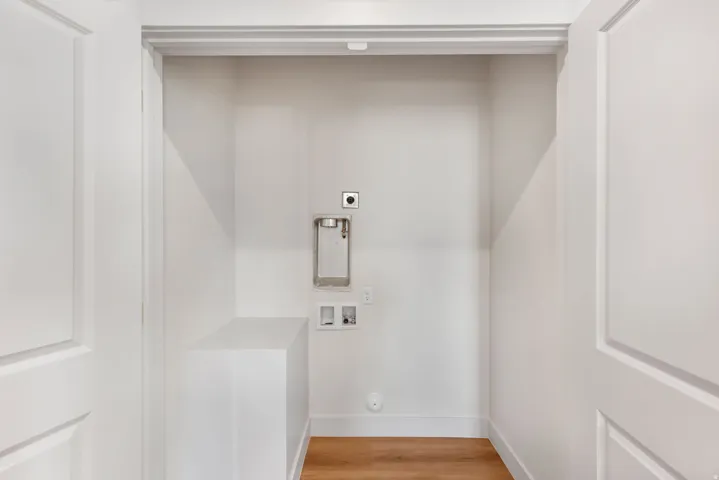 Dedicated laundry area featuring wood-finish flooring and a white built-in counter