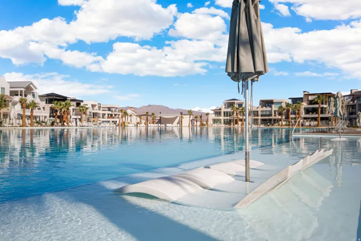 Expansive pool with submerged lounge seating and a built-in umbrella
