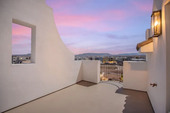 Balcony with a stucco finish, wrought iron railing, and a wall-mounted sconce