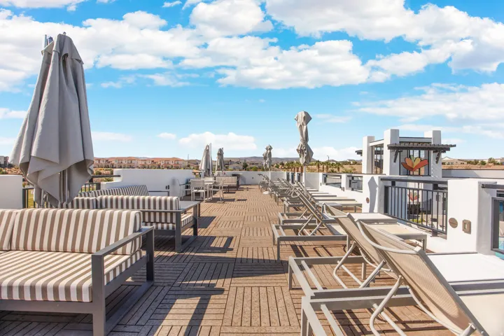 Expansive rooftop deck featuring wood-finish flooring, white stucco walls, and black metal railings