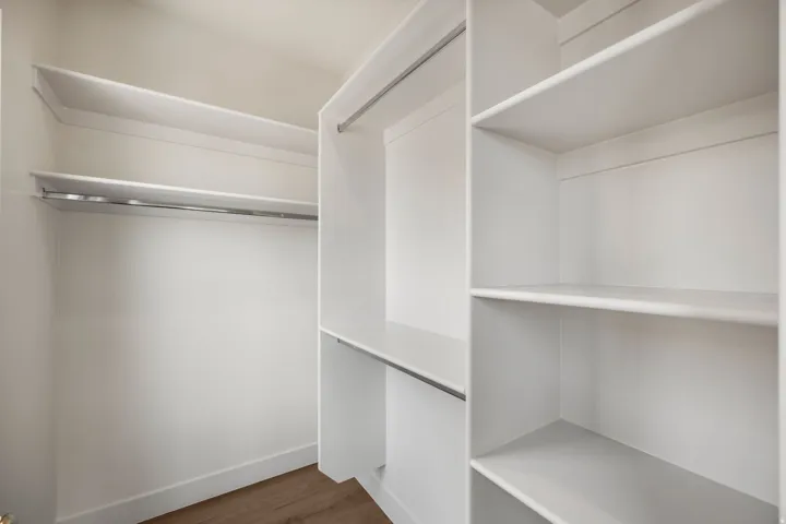 Integrated shelving and hanging rods in a white finish, complemented by wood-finish flooring