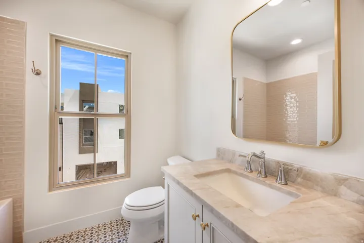 Vanity with a light-toned stone countertop, undermount sink, and chrome faucet