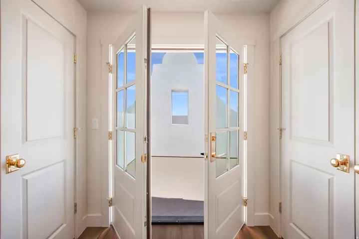 Wood-finish flooring, white paneled doors, and gold-finish hardware
