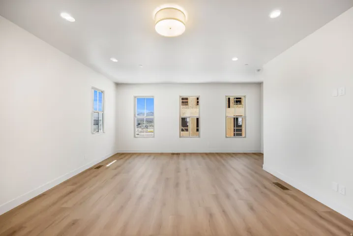 Recessed lighting, central ceiling light fixture, wood-finish flooring, and multiple windows