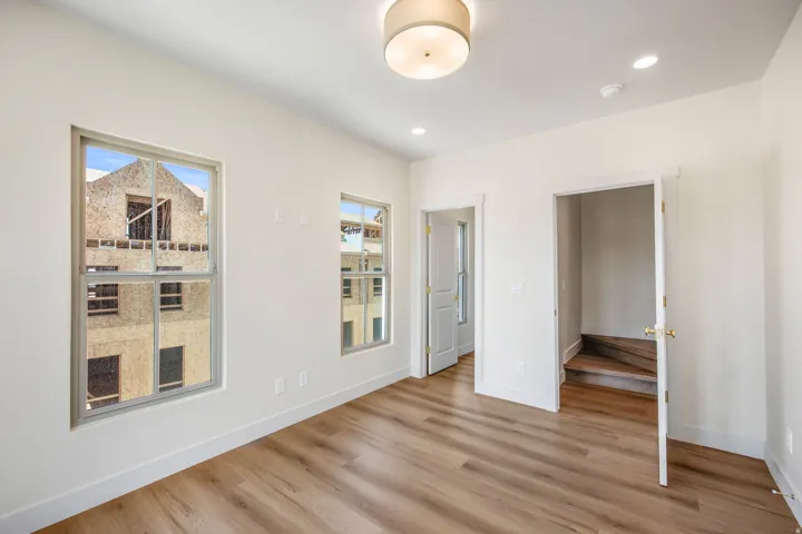 Bright room featuring two windows, wood-finish flooring, a flush mount ceiling light, and recessed lighting