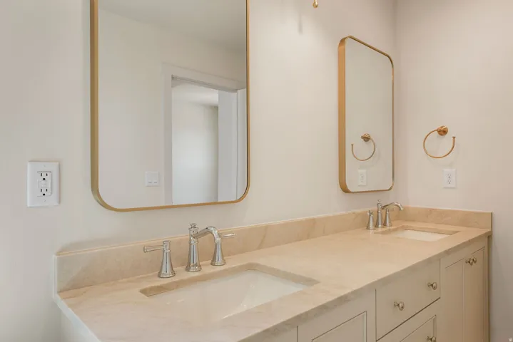 Dual vanity with integrated sinks, stone countertop, brushed nickel faucets, and framed mirrors