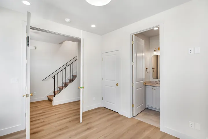 Wood-finish flooring throughout, white interior doors, recessed lighting, and a powder room featuring a single vanity with a stone countertop