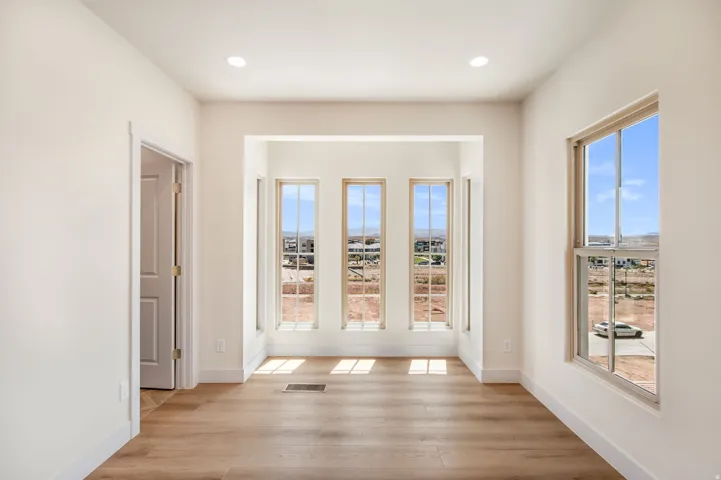 Recessed lighting, wood-finish flooring, white trim, multiple windows, and a panel door