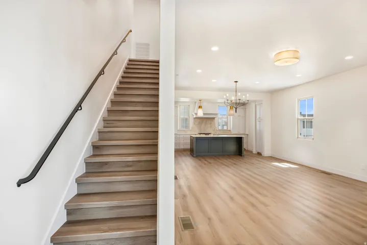 Wood-finish flooring throughout, an open concept layout, and a contemporary kitchen featuring an island with a light-colored countertop
