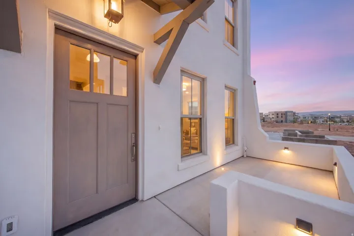 Entry with a paneled door featuring glass inserts, an overhead porch light, and an adjoining private patio