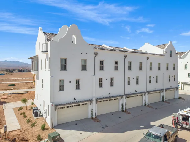 White stucco exterior with multiple garage bays, individual balconies, and a tile roof
