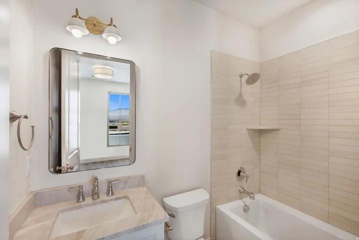 Bathroom featuring a vanity with an integrated sink, a rectangular mirror, and a built-in bathtub with tiled surrounds