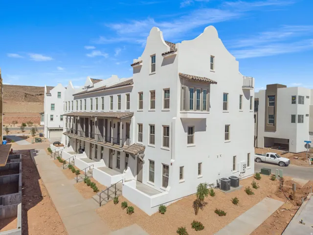 White stucco exterior with multiple balconies, a bay window, and a tiled overhang
