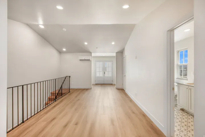 Wood-finish flooring throughout, recessed lighting, and a split AC unit