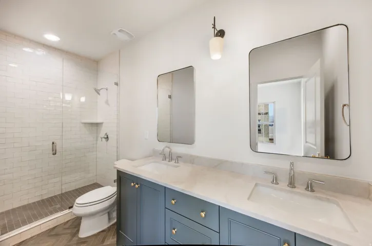 Dual vanity with undermount sinks, stone countertop, and two framed mirrors