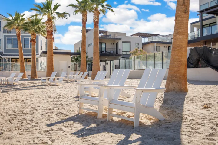 Expansive sand area featuring multiple palm trees and modern residential structures