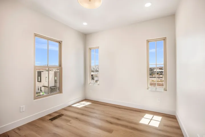 Wood-finish flooring with multiple windows, recessed lighting, and a semi-flush mount ceiling fixture