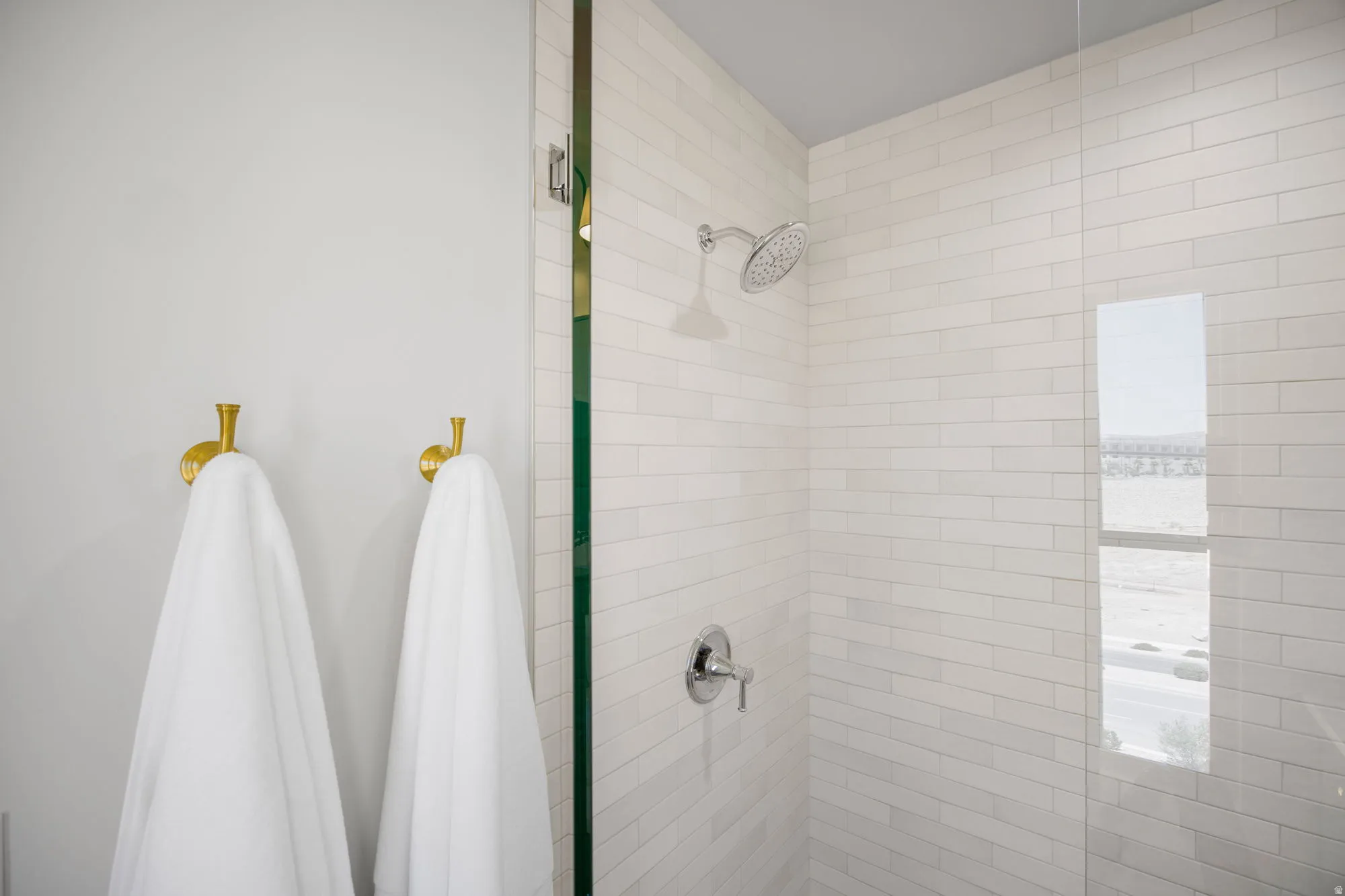 Shower with subway tile surround, chrome fixtures, and glass enclosure