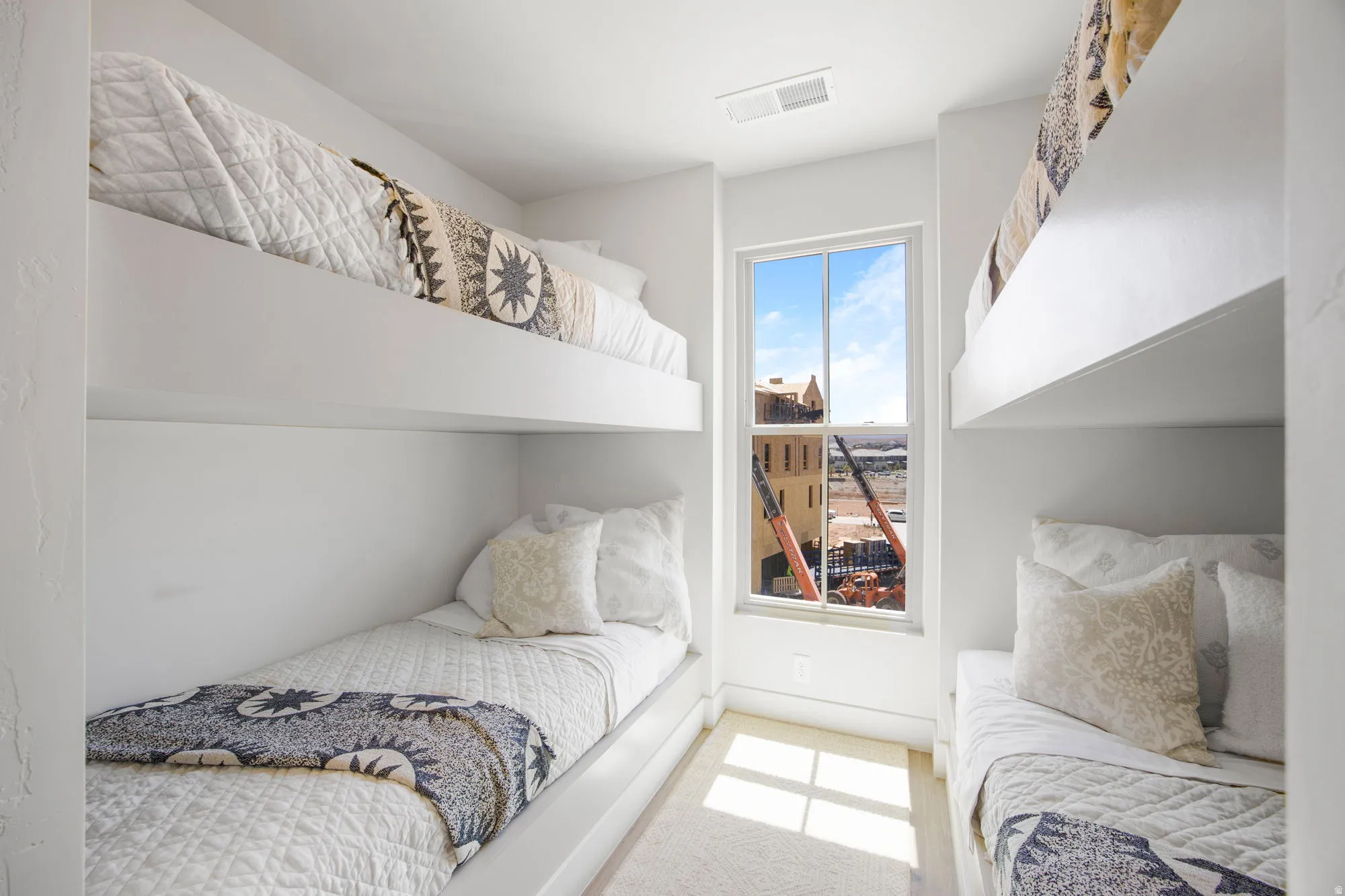 Built-in bunk beds with integrated platforms, white painted walls, and a window providing natural light