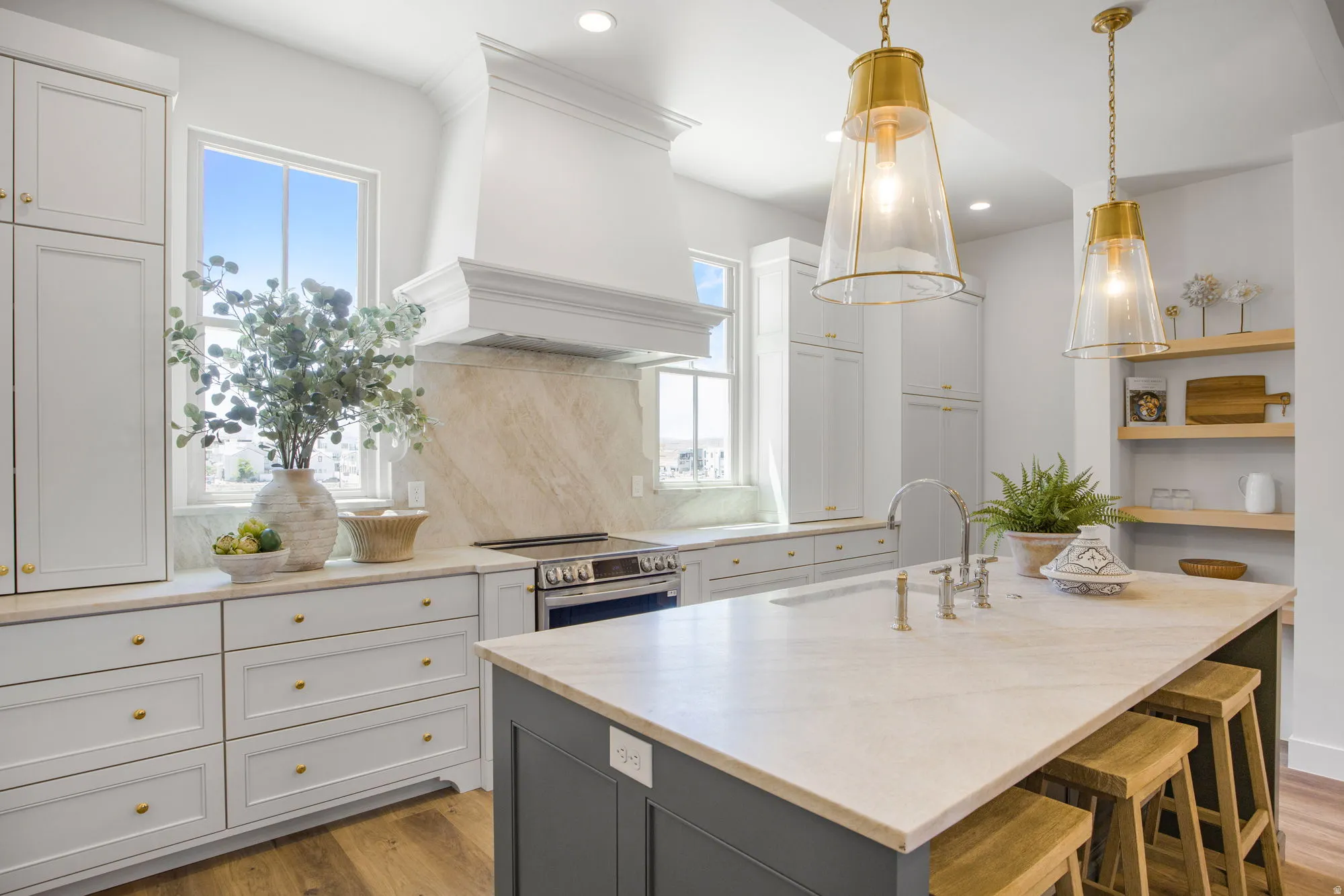 Kitchen featuring a built-in range, stone countertops, light-toned cabinetry, a custom range hood, and pendant lighting