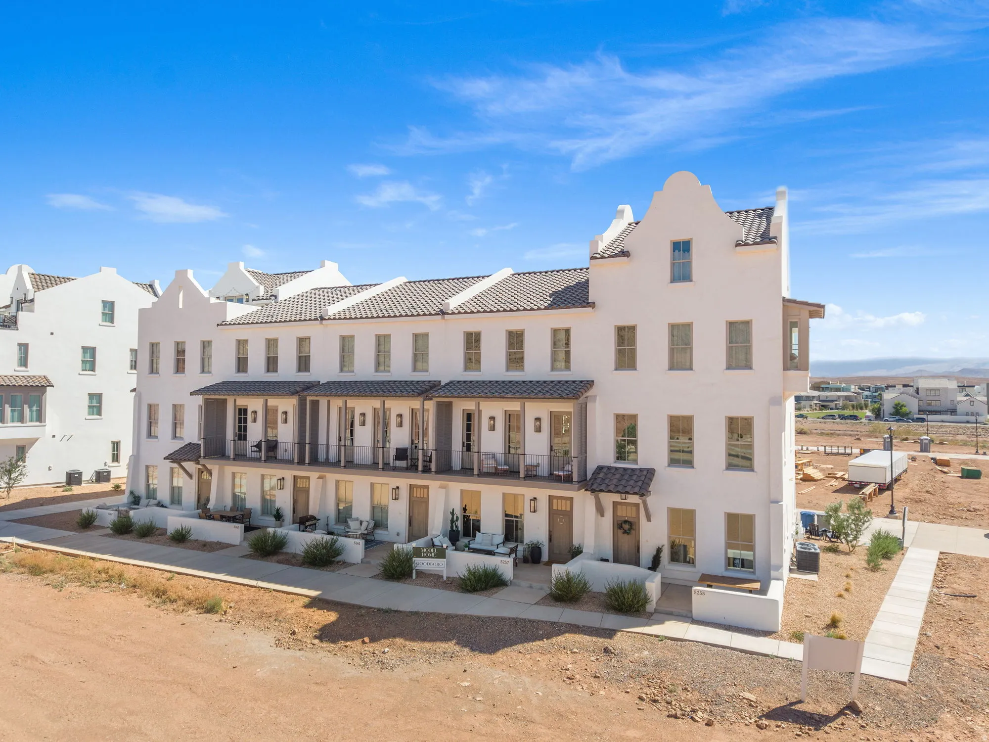 White stucco exterior with multiple balconies, tile roofing, and a prominent gable