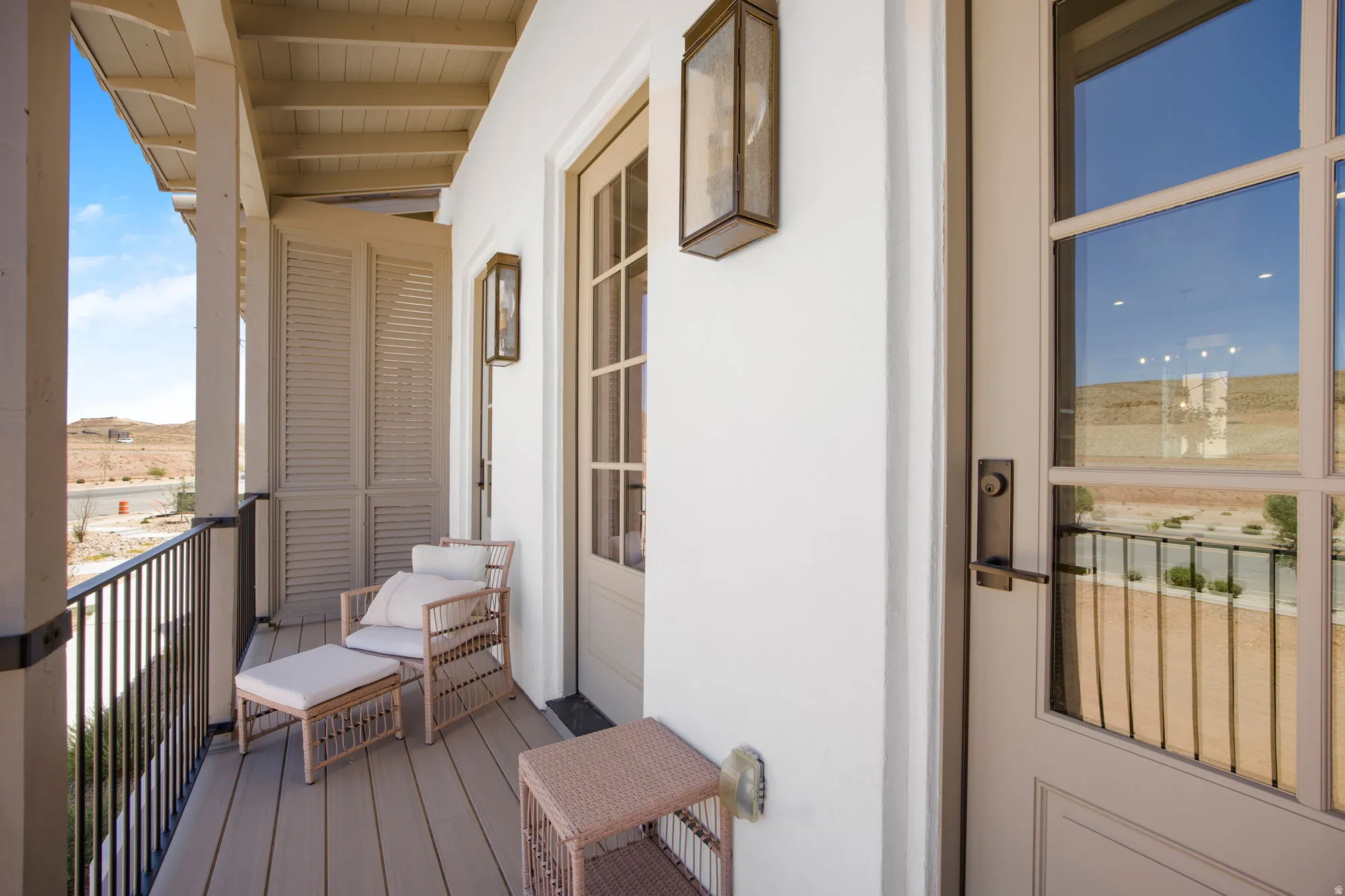 Exterior balcony featuring wood-finish decking, dark metal railing, and exposed beam ceiling