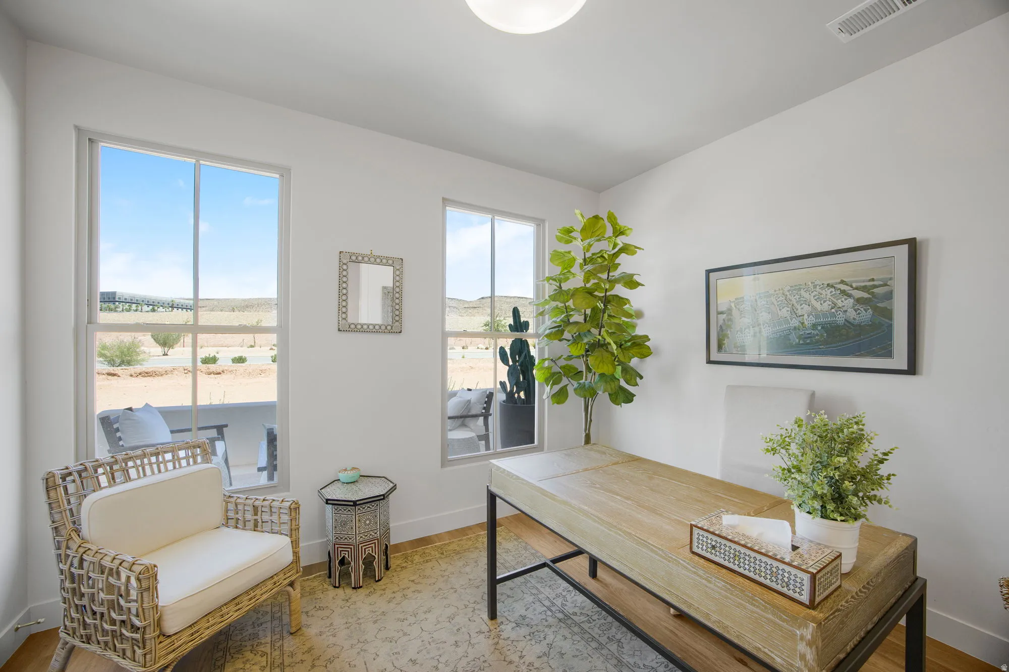 Light-filled interior space with two large windows, wood-finish flooring, and a flush-mount ceiling light