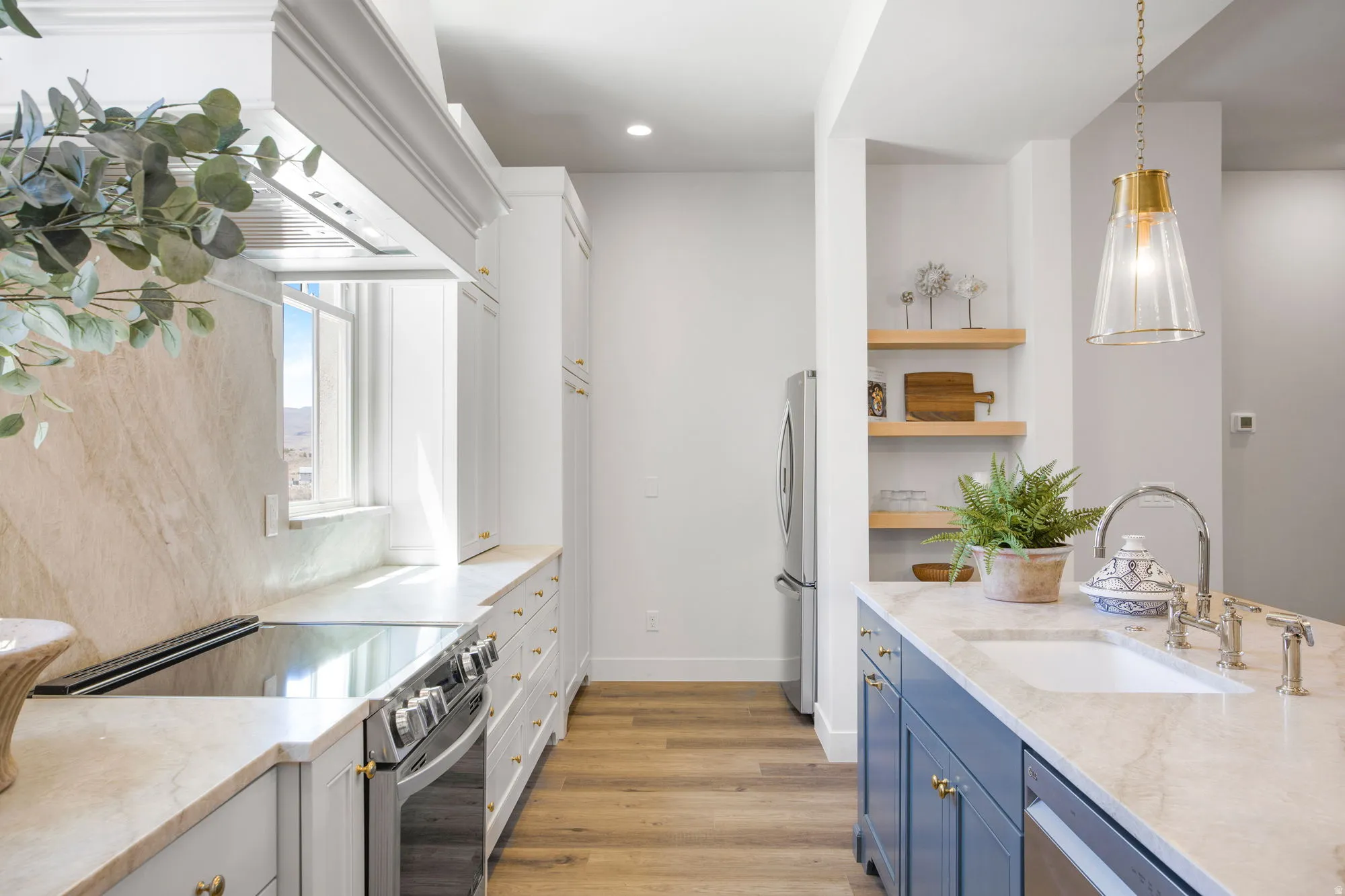 Kitchen with wood-finish flooring, light-toned countertops, white upper cabinetry, and blue lower cabinetry