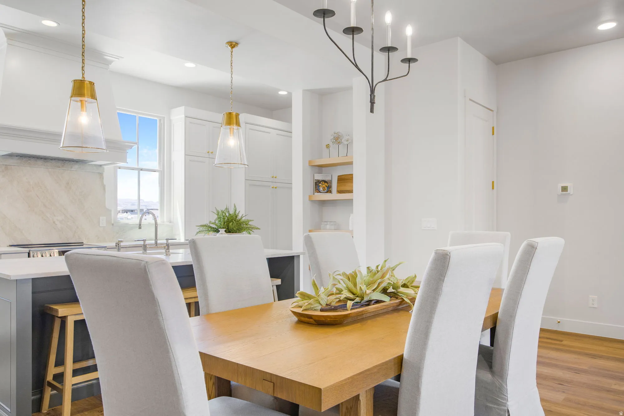 Hardwood flooring, kitchen island with seating, white cabinetry, integrated range hood, and open shelving
