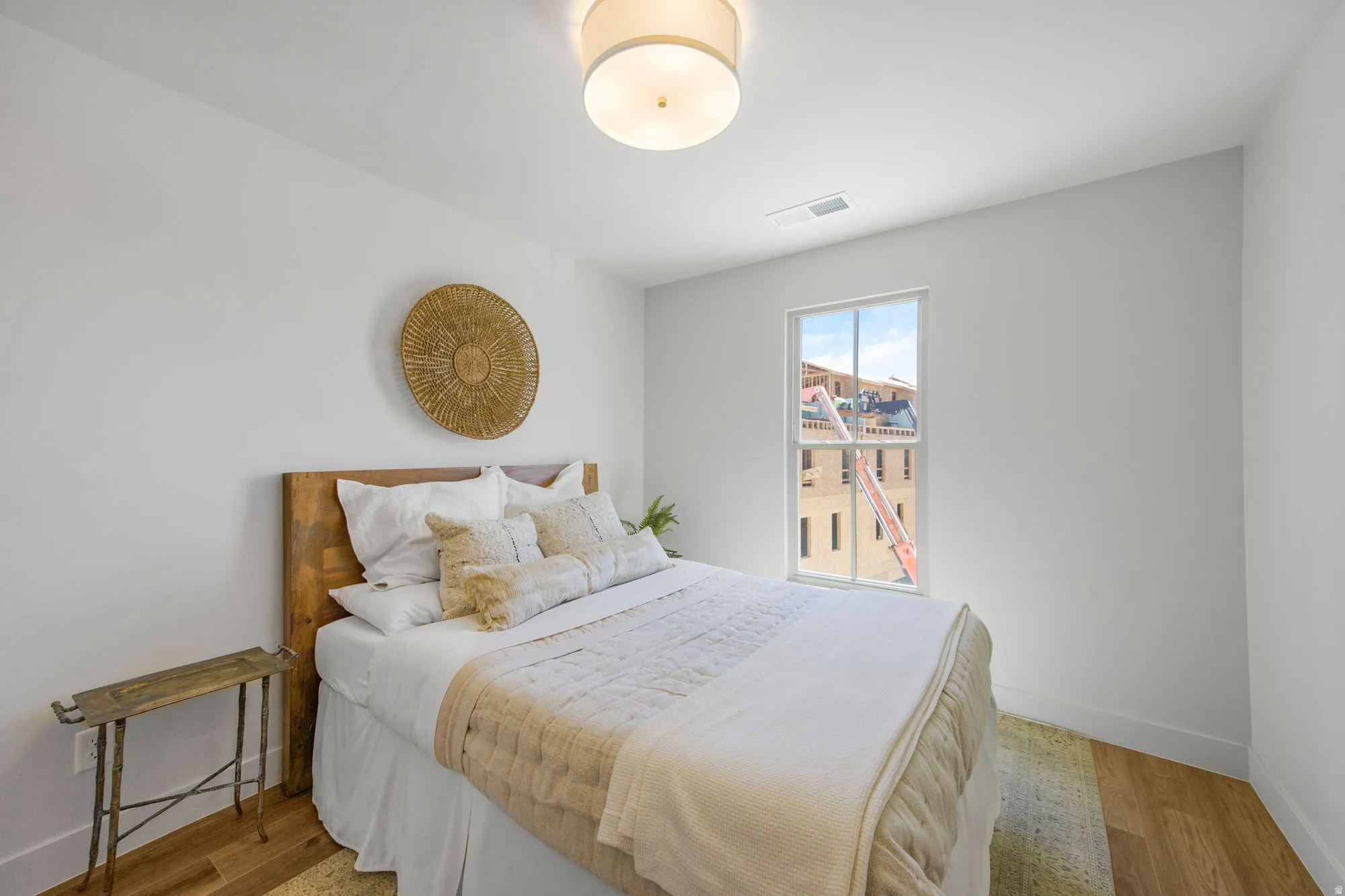 White walls, single window, wood-finish flooring, and a ceiling-mounted light fixture