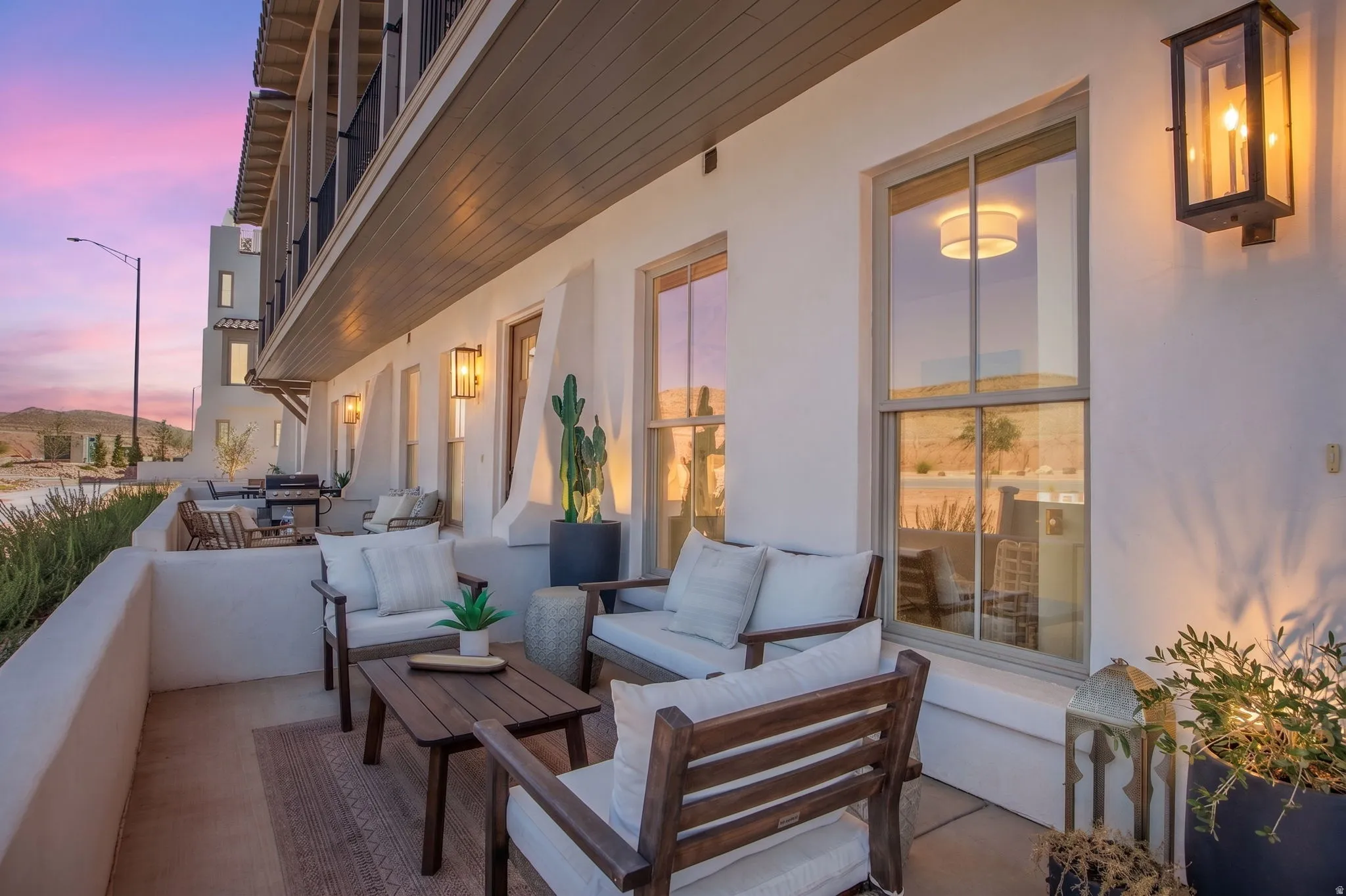 Patio featuring a stucco wall, mounted light fixtures, wood-finish overhead soffit, and multiple windows