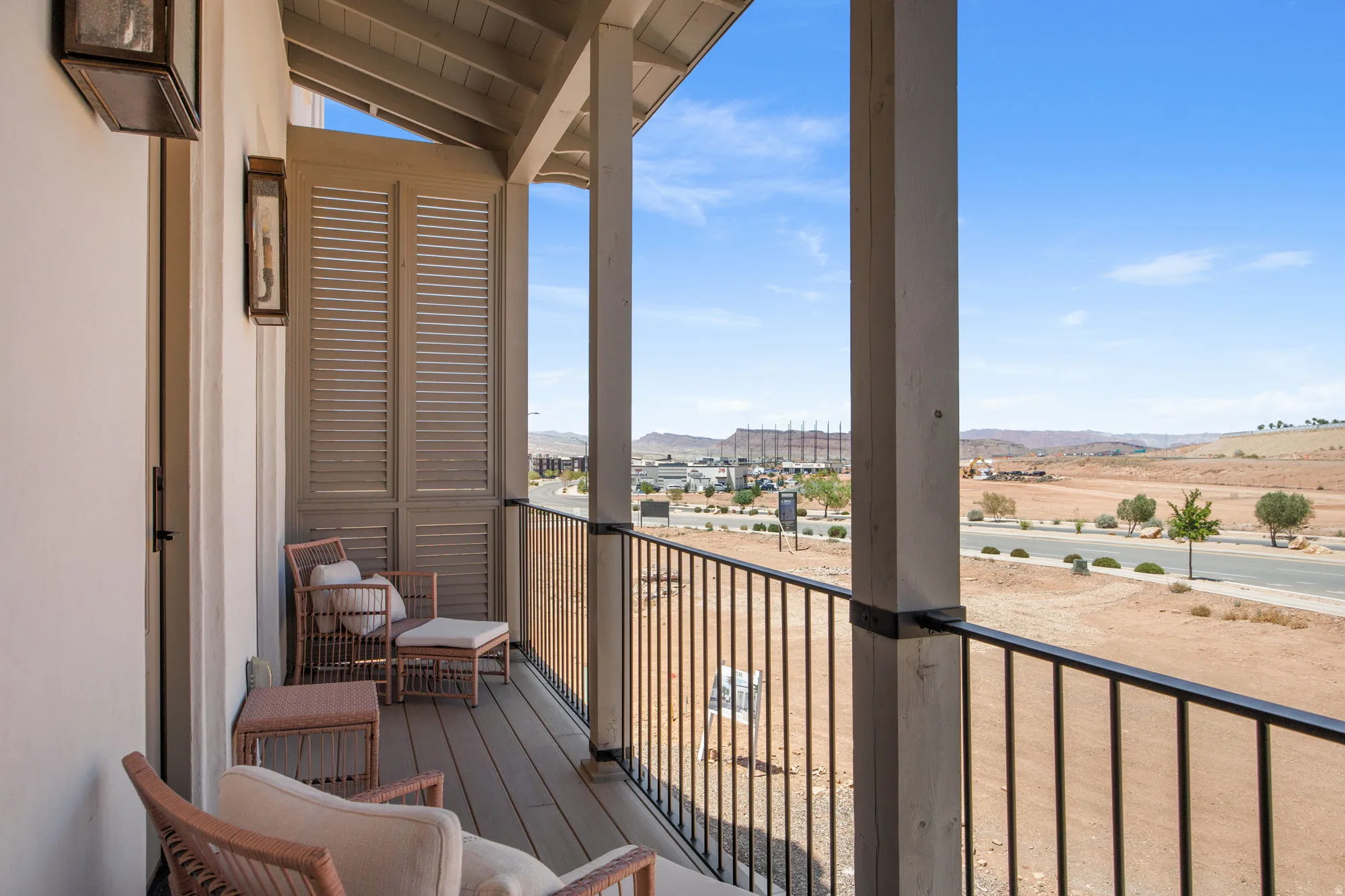 Balcony featuring wood-finish decking, wrought iron railing, and decorative exterior lighting