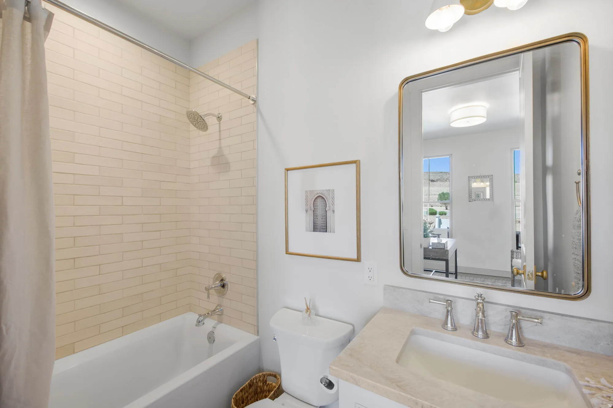 Bathtub with subway tile surround, polished chrome fixtures, vanity with stone countertop, integrated sink, and an unframed rectangular mirror