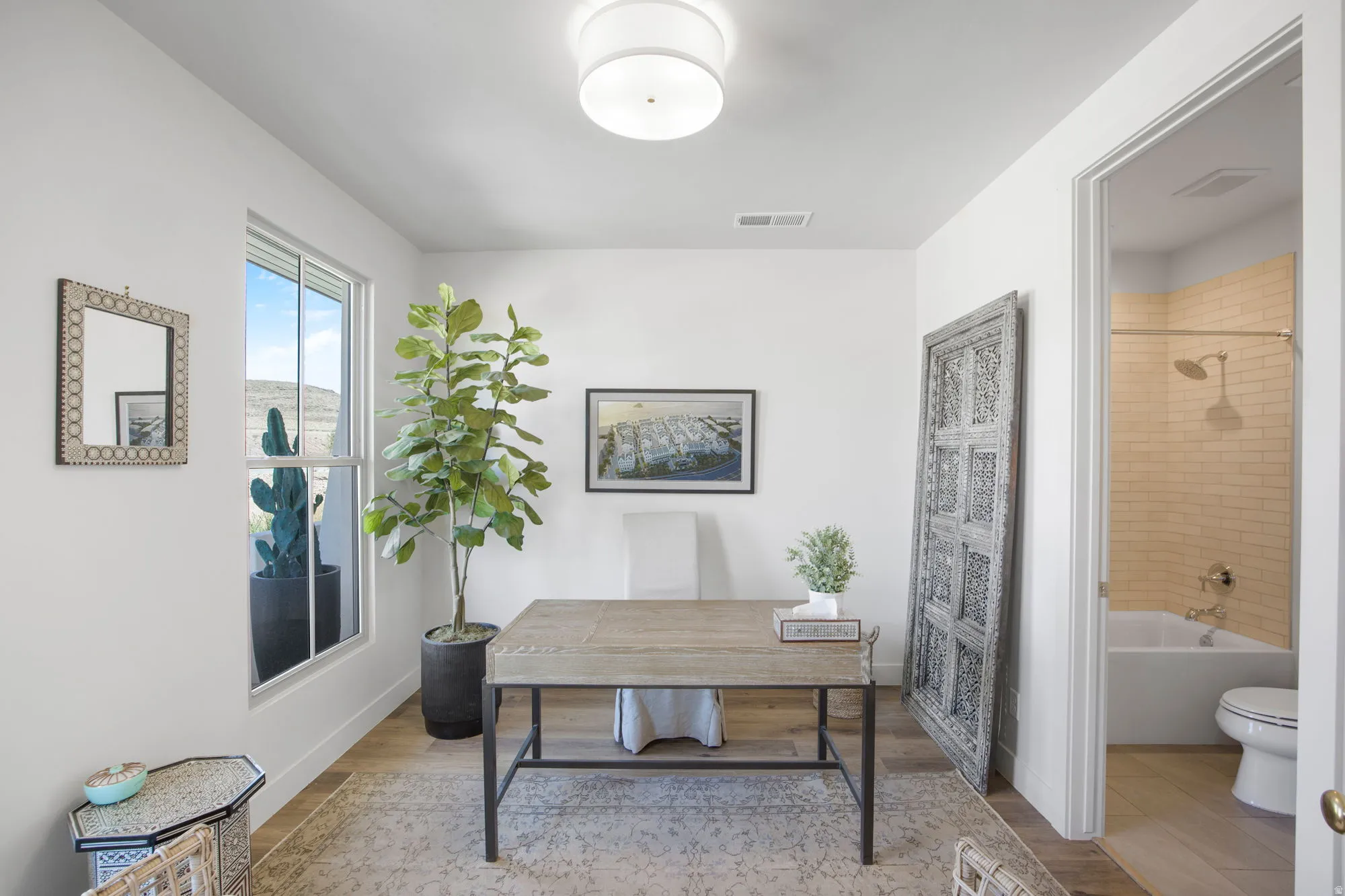 White walls with a single window, a flush-mount ceiling light, and wood-finish flooring