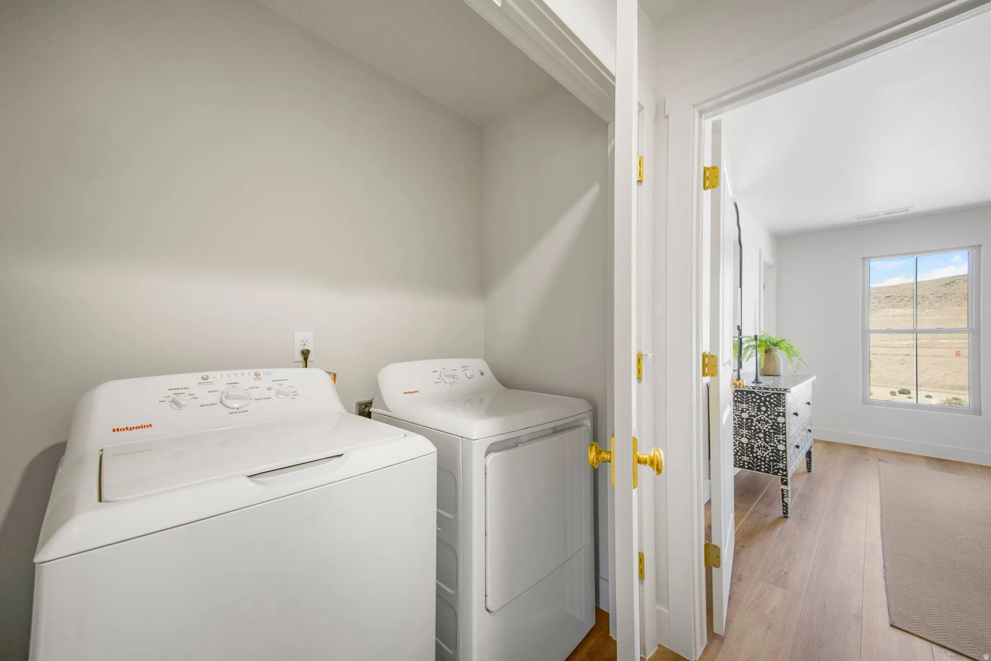 Laundry closet with a white washer and dryer, featuring a light-toned interior, and wood-finish flooring